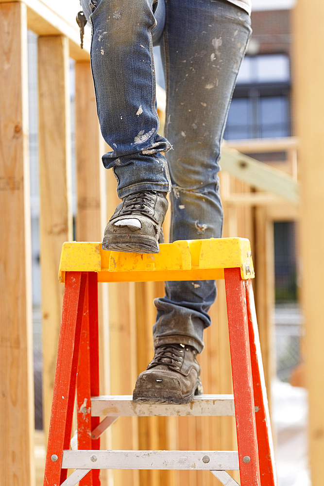 Legs of Caucasian woman on ladder at construction site