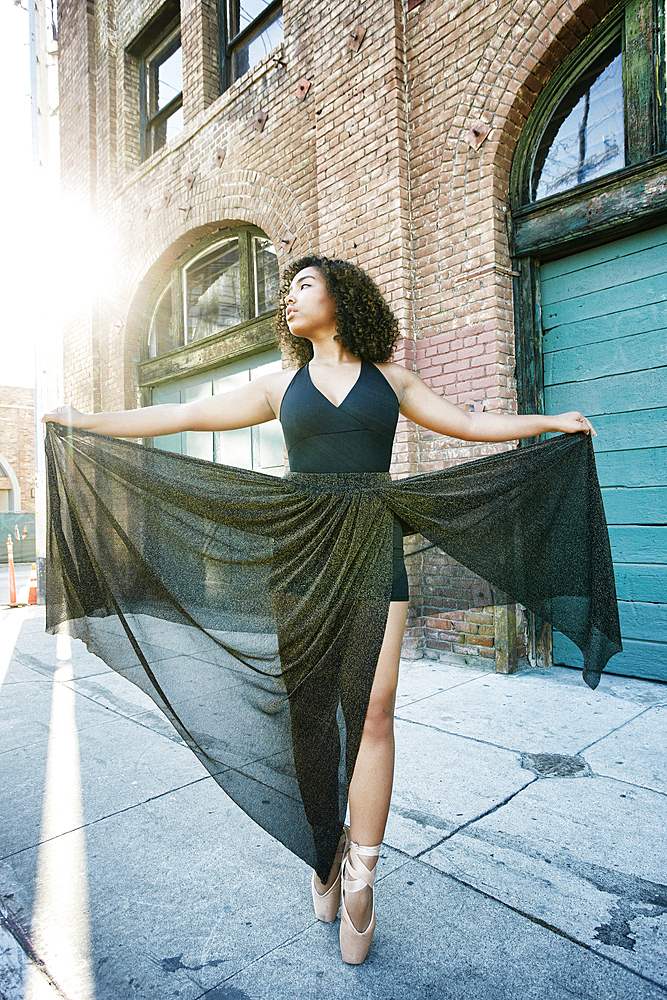 Sunbeams on mixed race woman dancing in city