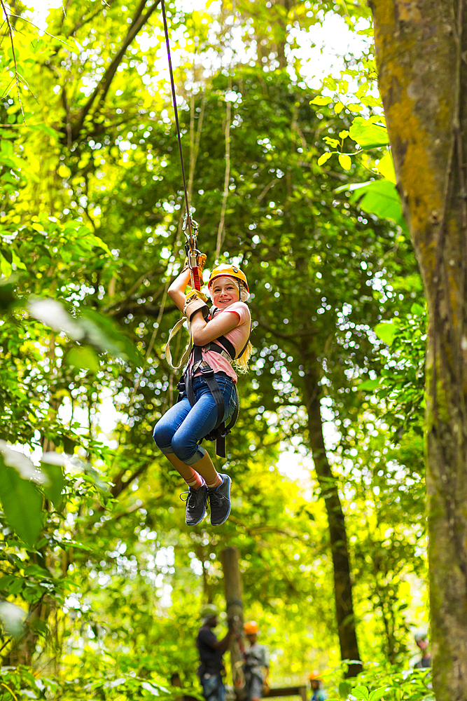 Caucasian girl hanging on zip line in forest