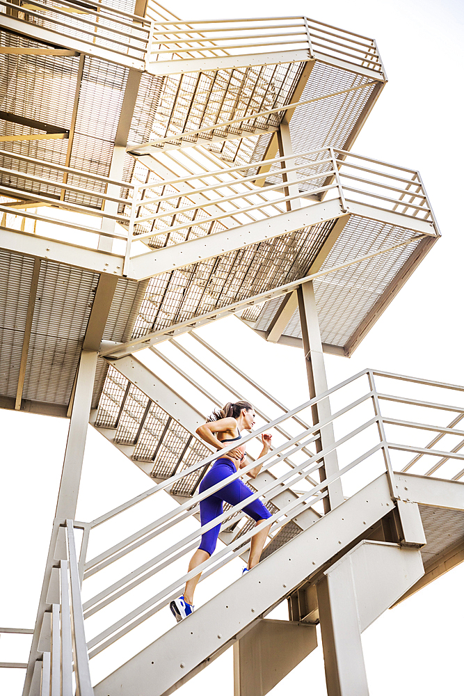 Caucasian woman running on urban staircase