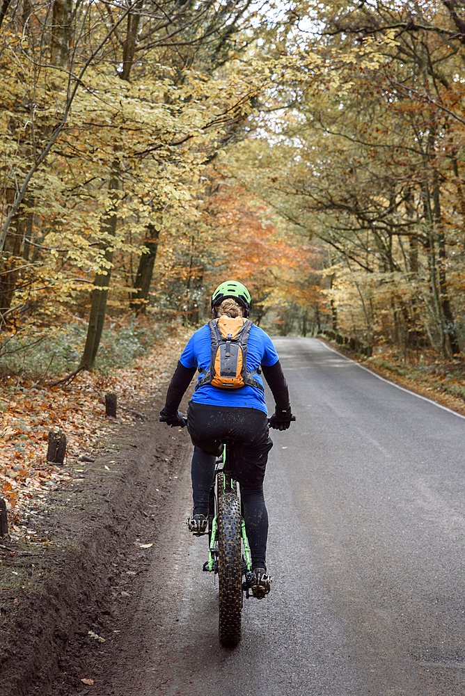 Caucasian woman riding bicycle on forest road