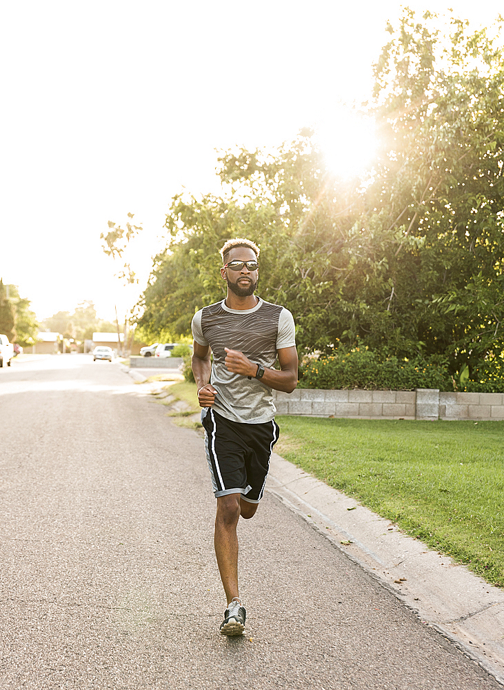 Black man running on street in neighborhood