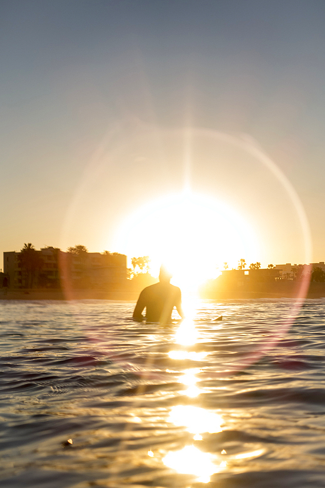 Caucasian man sitting on surfboard in ocean