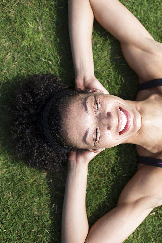 Mixed Race woman laying on grass relaxing,