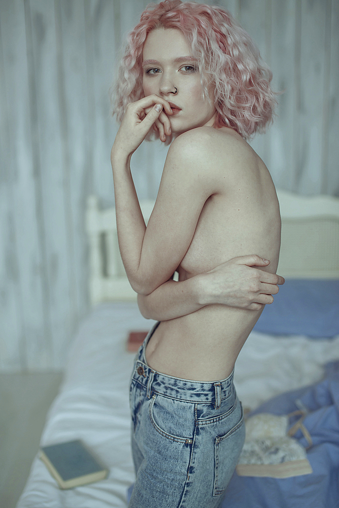 Portrait of pensive topless Caucasian woman in bedroom