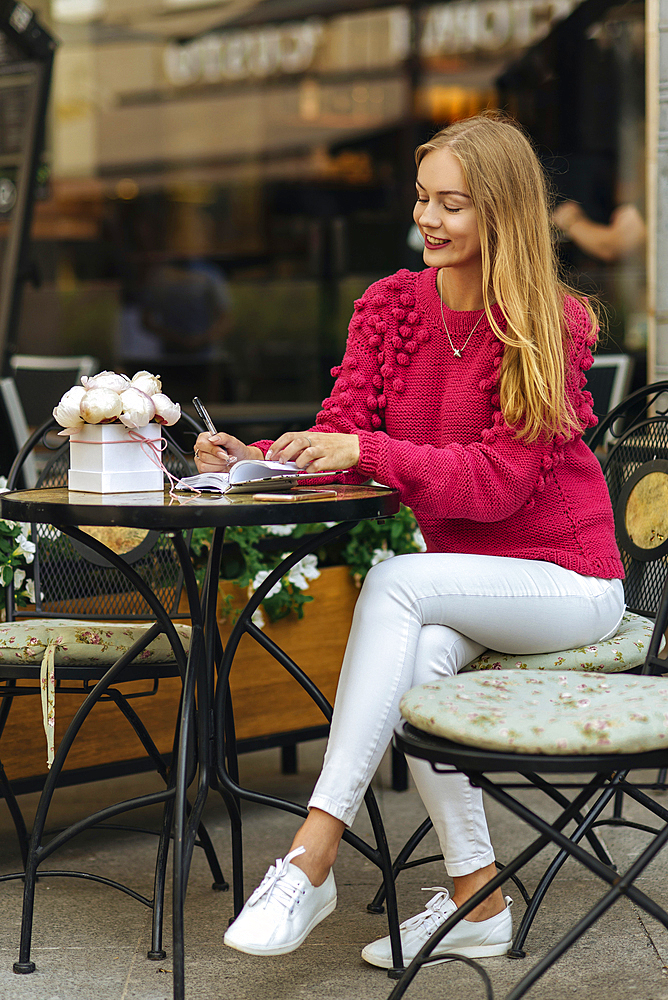 Caucasian woman sitting at table writing in journal