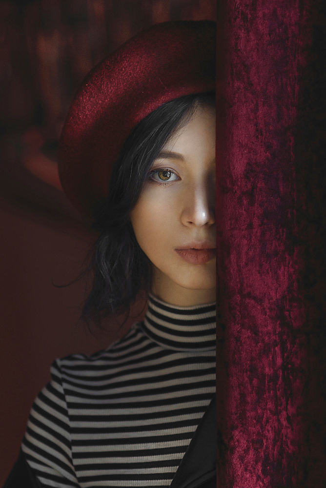 Caucasian woman peeking from behind curtain