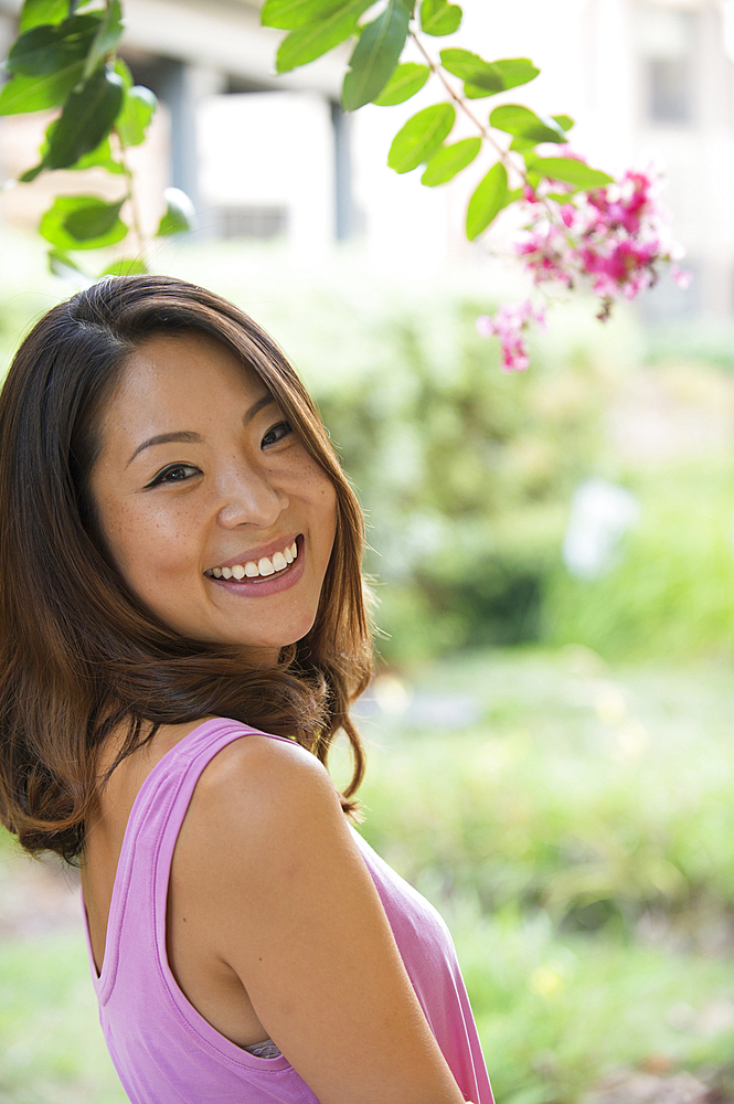 Portrait of smiling Asian woman outdoors near flowers