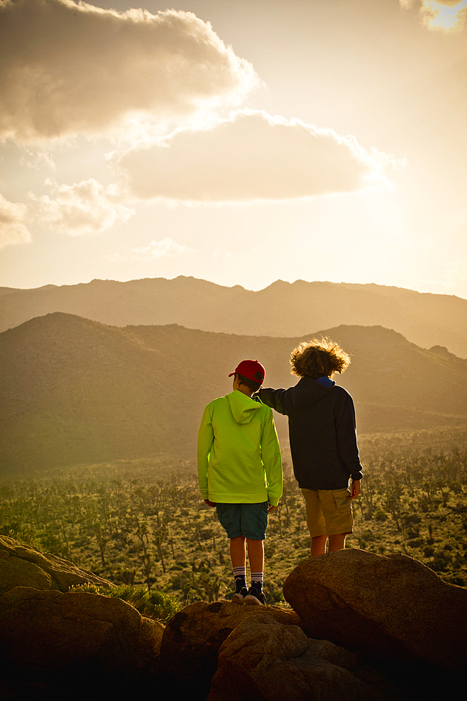 Boys standing on rock admiring desert landscape