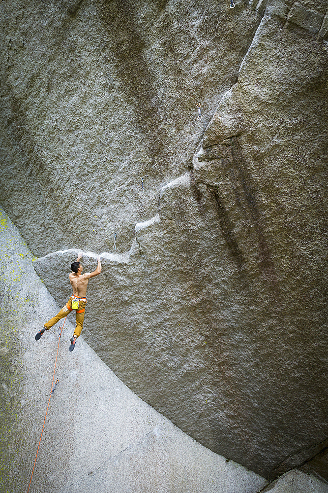 Mixed race boy hanging from rock