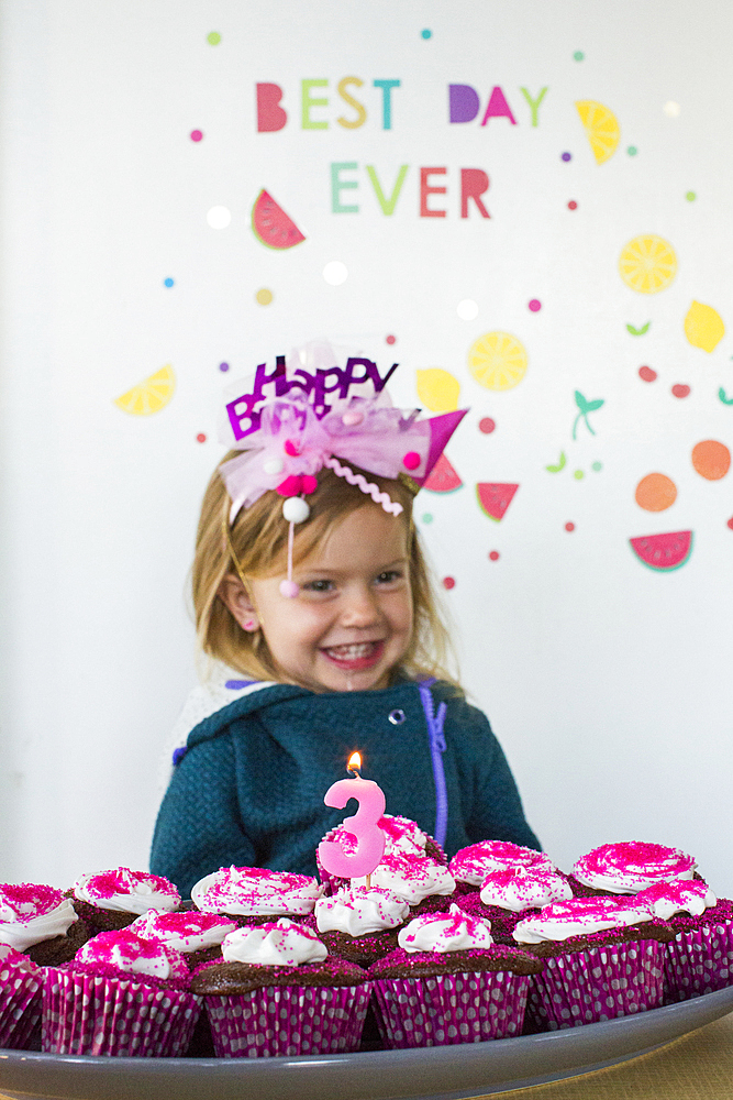 Caucasian girl holding tray of cupcakes for birthday