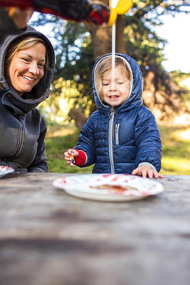 Caucasian mother pouring syrup on pancake for daughter