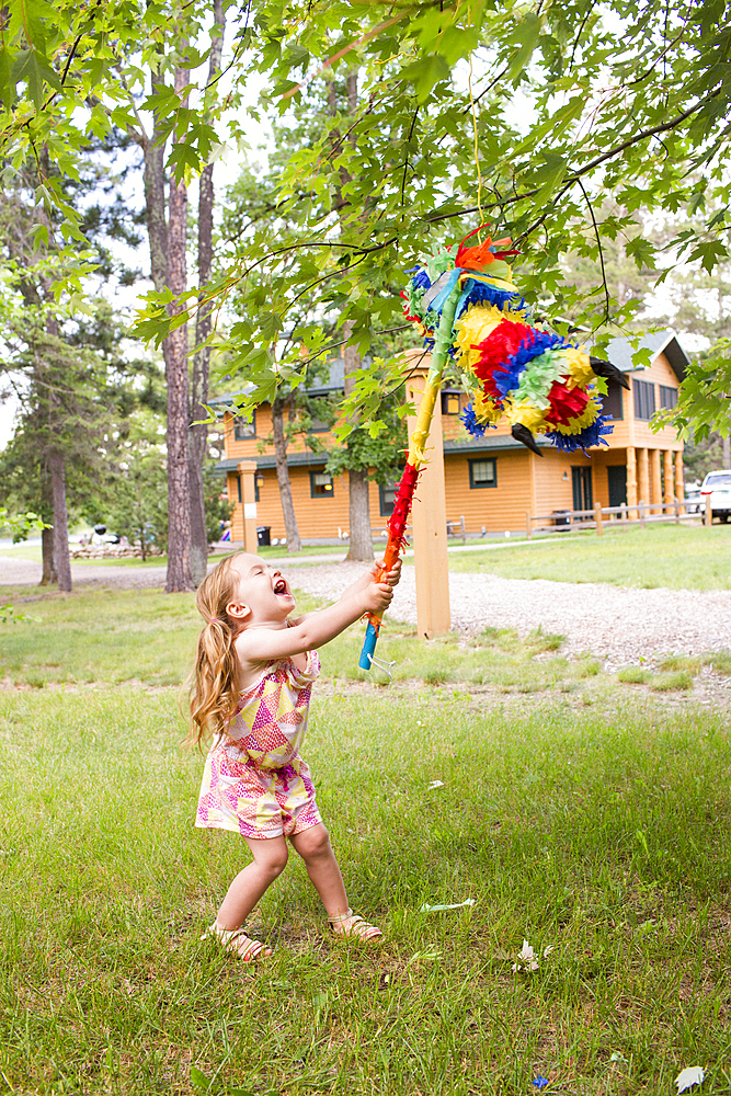 Laughing Caucasian girl hitting pinata outdoors