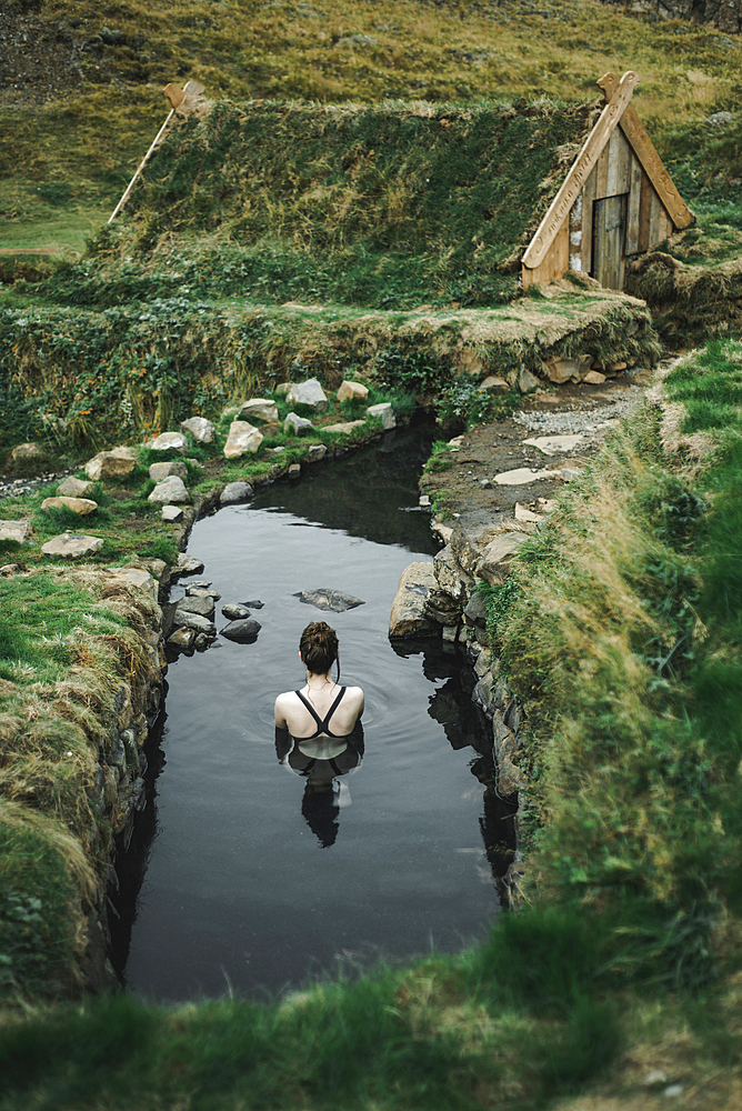 Caucasian woman swimming in pond near rural house