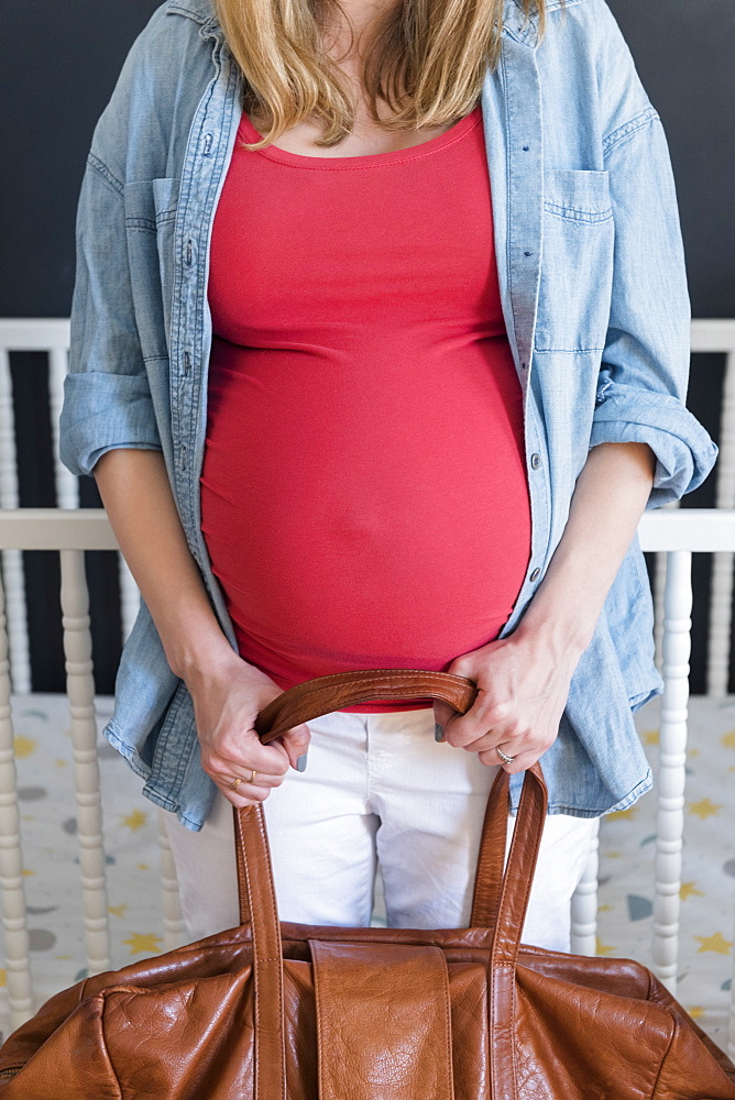 Caucasian expectant mother carrying bag