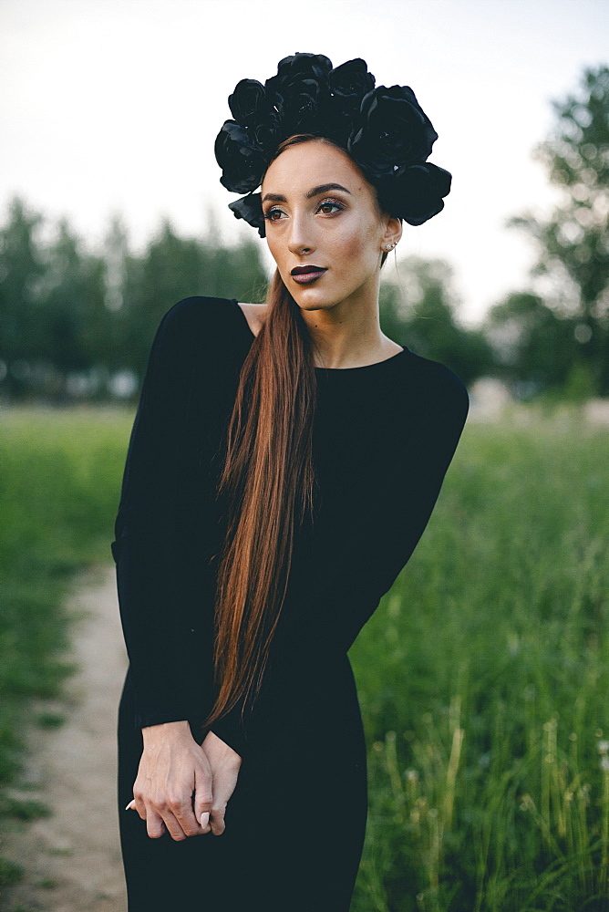 Middle Eastern woman wearing black dress on path in woods