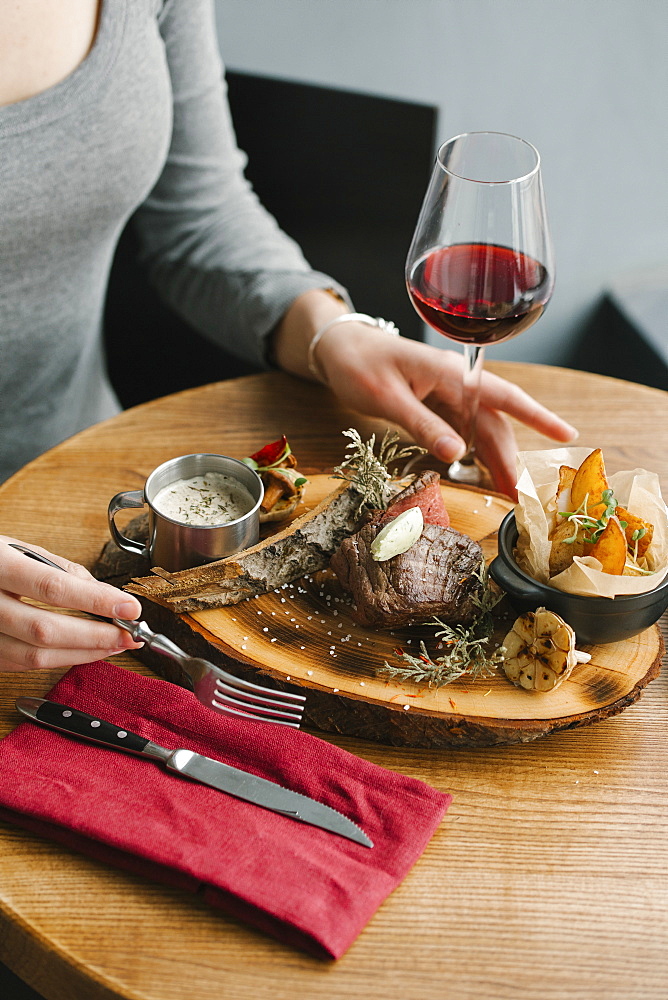 Woman eating meat with red wine