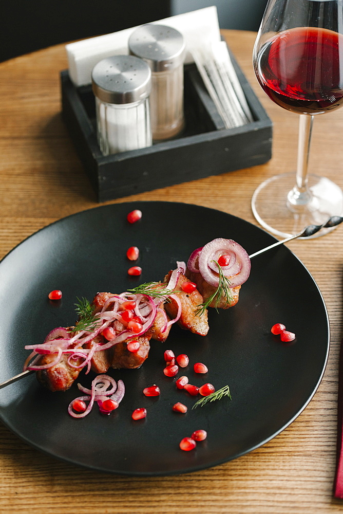 Meat on skewer with pomegranate seeds and red wine