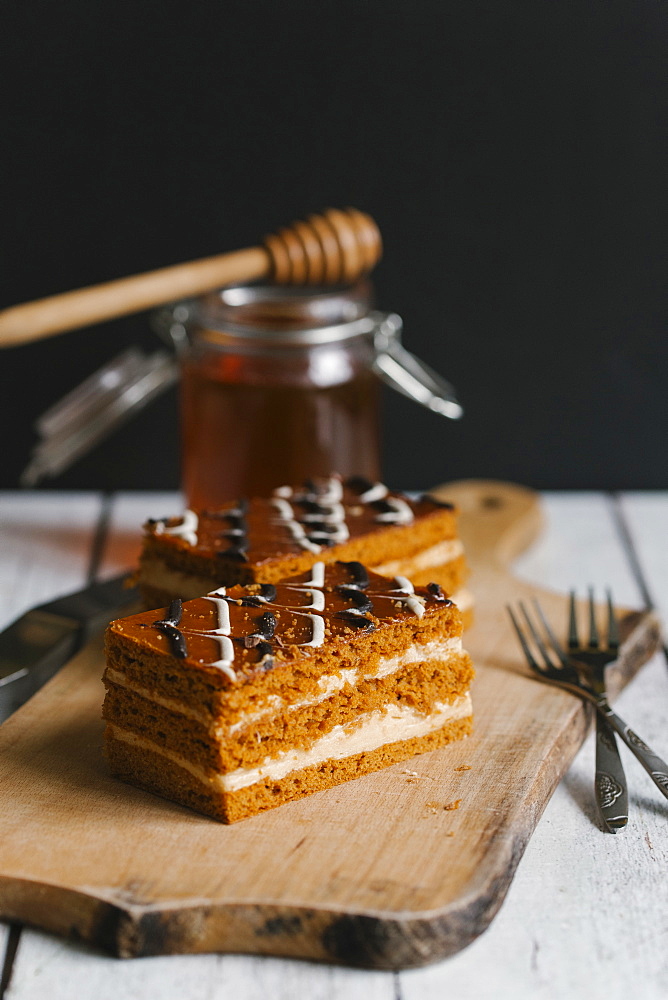 Slices of layer cake on cutting board with honey