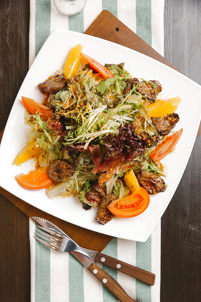 Meat with tomatoes and oranges on plate