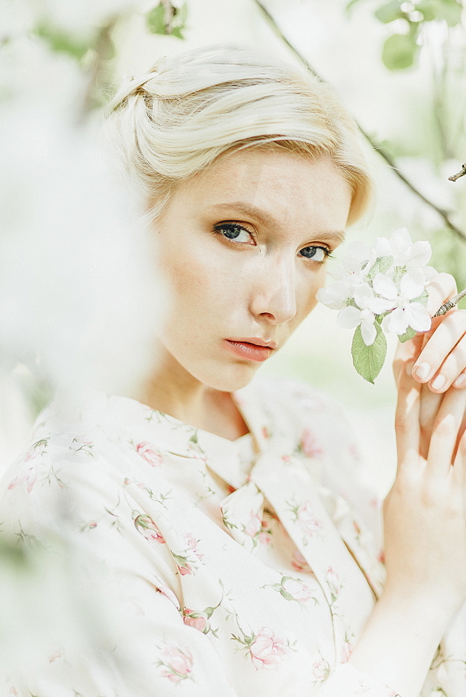 Middle Eastern woman holding flowers on tree