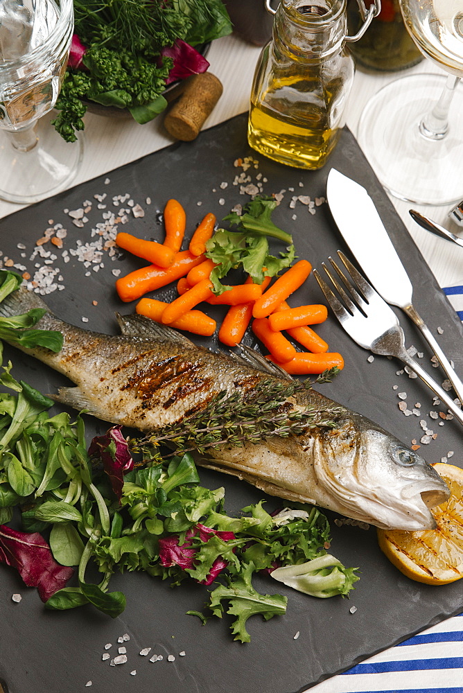 Grilled fish and salad on stone plate