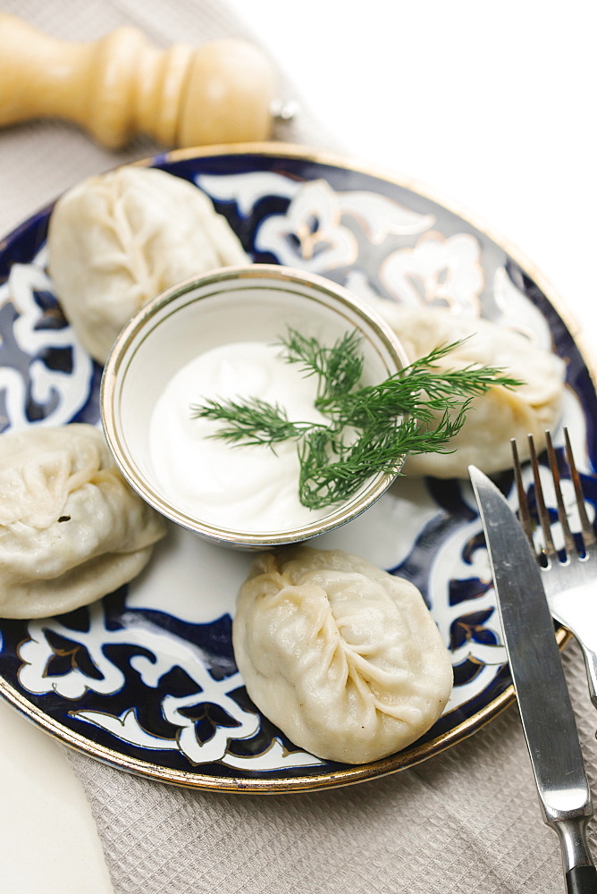 Dumplings and sauce on plate with fork and knife