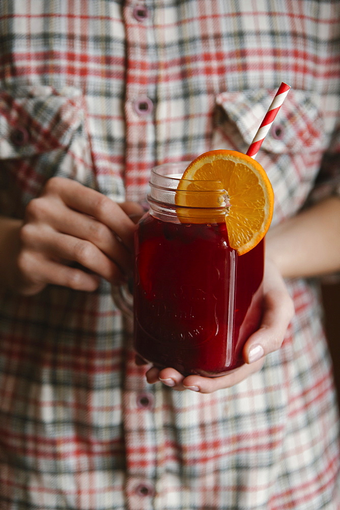 Woman holding glass of fruit tea with straw