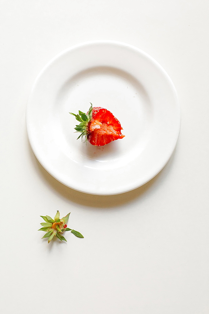 Bitten strawberry on white plate