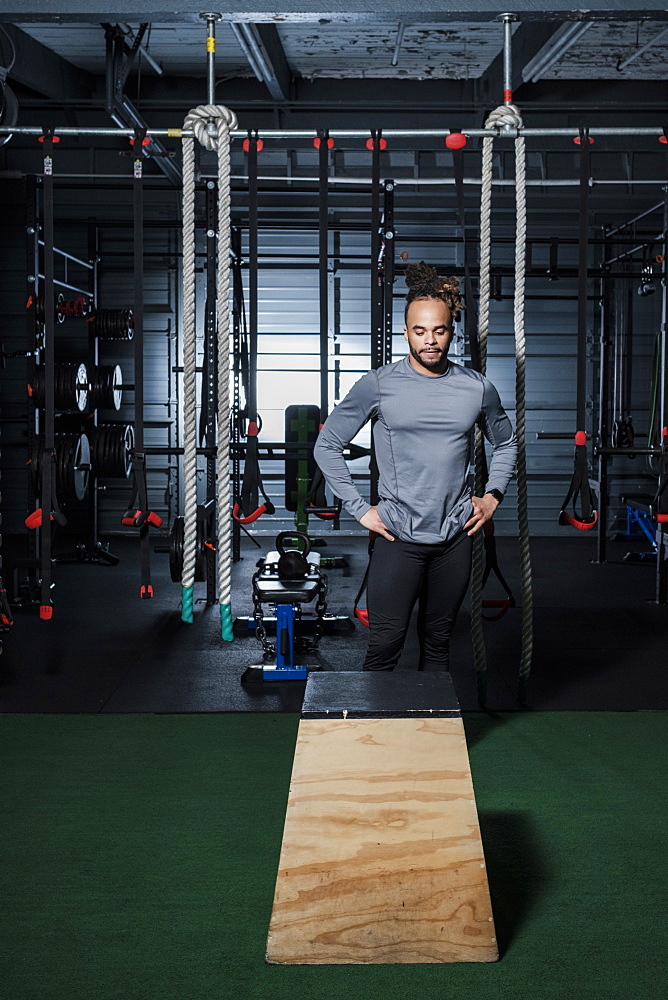 Mixed Race man looking at wooden platform in gymnasium