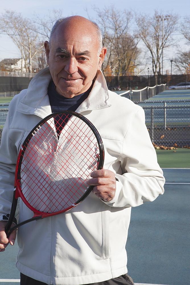 Smiling Hispanic man holding tennis racket