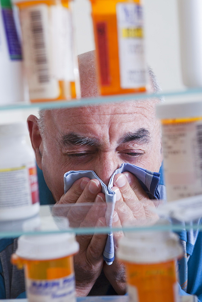 Hispanic man wiping nose near medicine cabinet