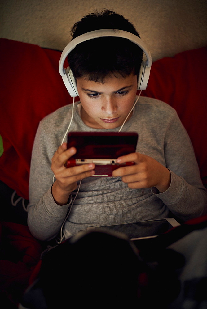 Hispanic boy listening to cell phone with headphones