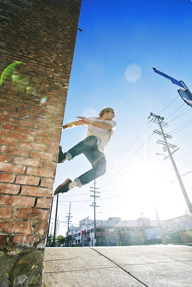 Caucasian man jumping on urban wall