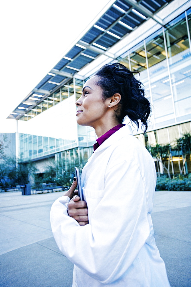 Portrait of smiling Mixed Race doctor holding digital tablet outdoors