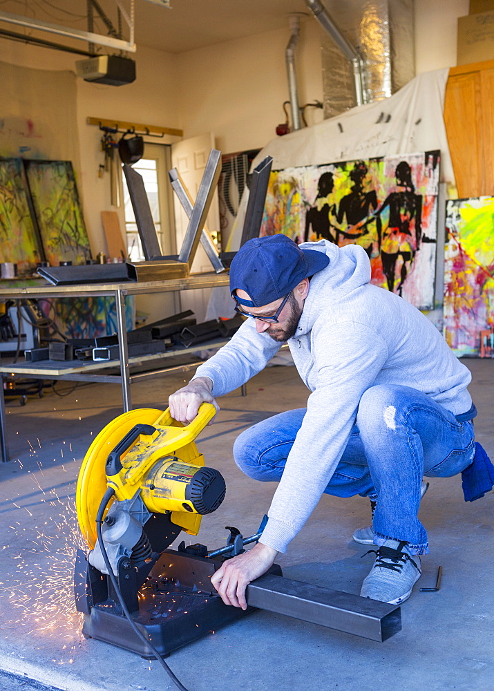 Caucasian man cutting metal with saw