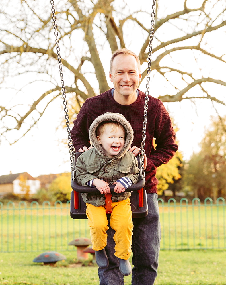 Caucasian father pushing son on swing