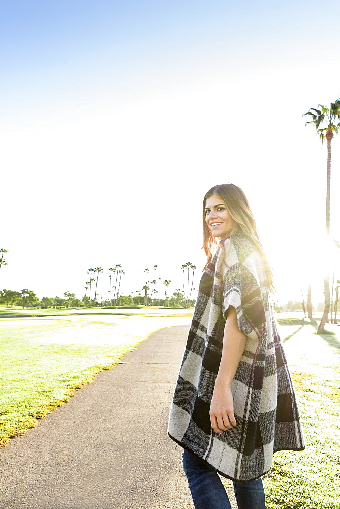 Hispanic woman wearing poncho walking on path