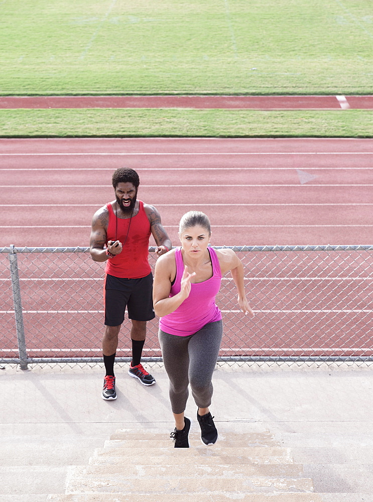 Trainer timing woman running on bleachers