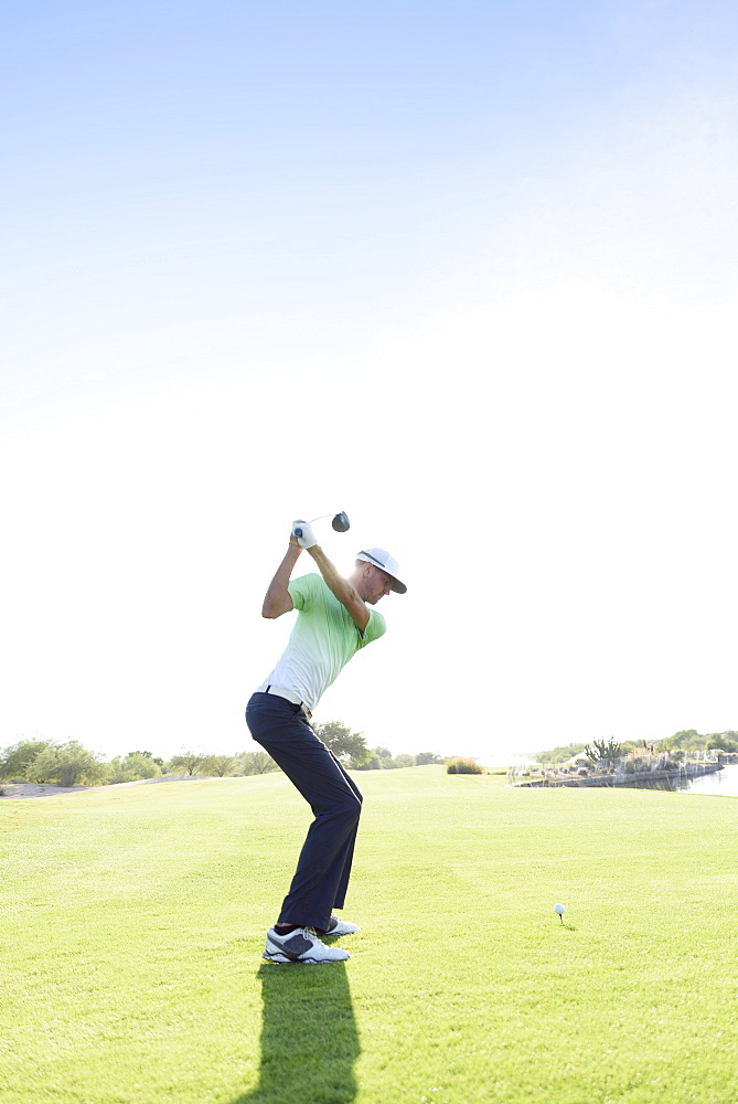 Caucasian man teeing off on golf course