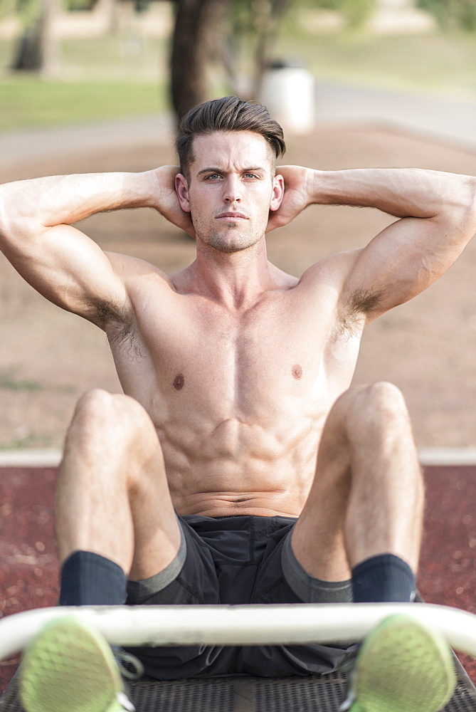 Caucasian man doing sit-ups outdoors