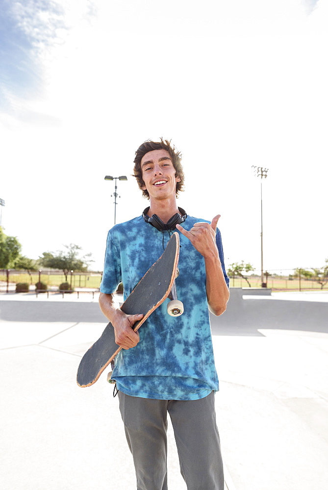 Portrait of smiling Hispanic man holding skateboard