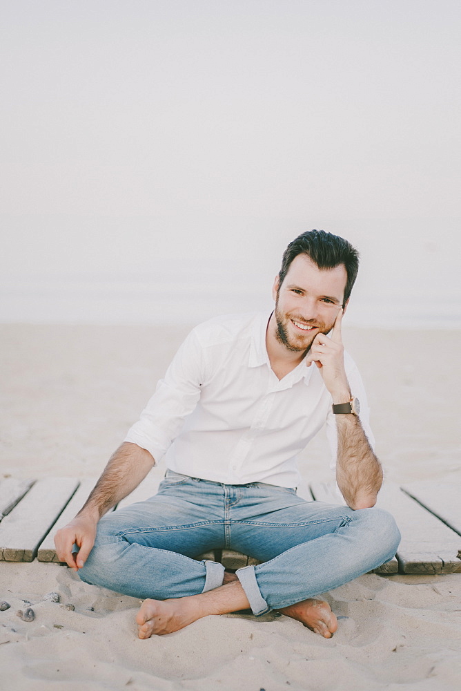 Caucasian man sitting on boardwalk at beach