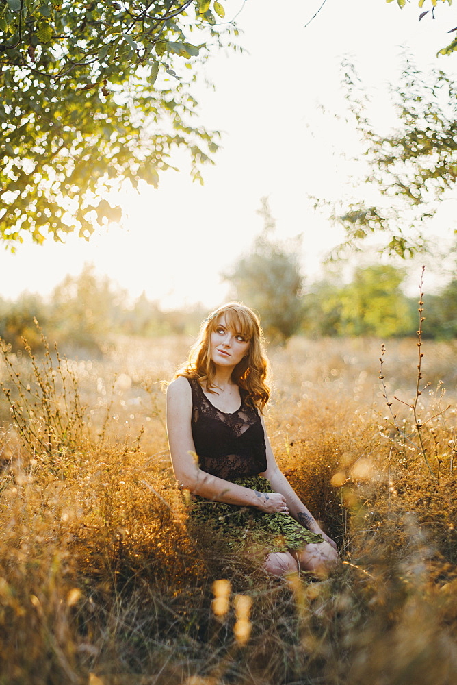 Pensive Caucasian woman kneeling in woods