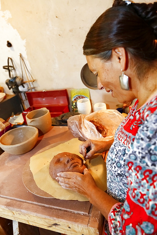 Mixed race woman shaping clay mask in art studio