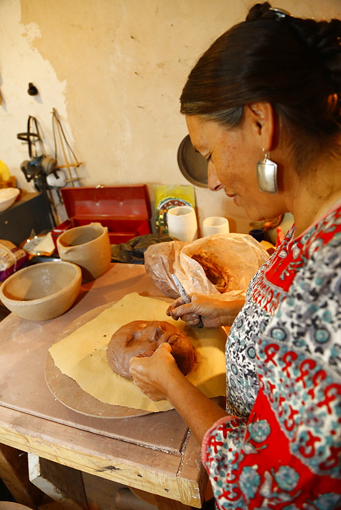 Mixed race woman shaping clay mask in art studio