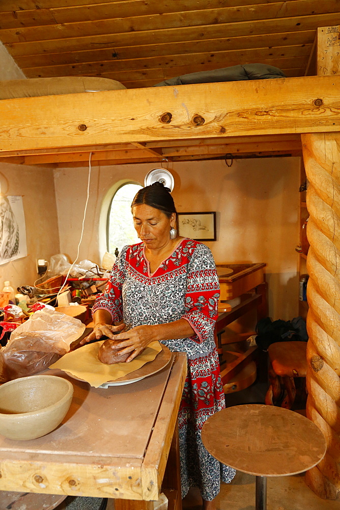 Mixed race woman shaping clay in art studio