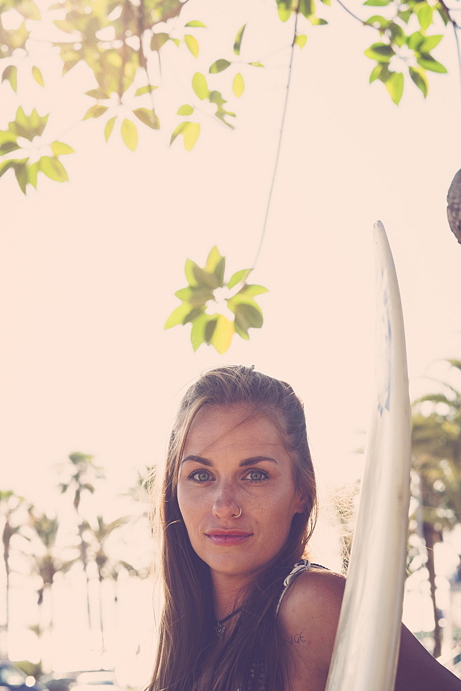 Portrait of Caucasian woman holding surfboard