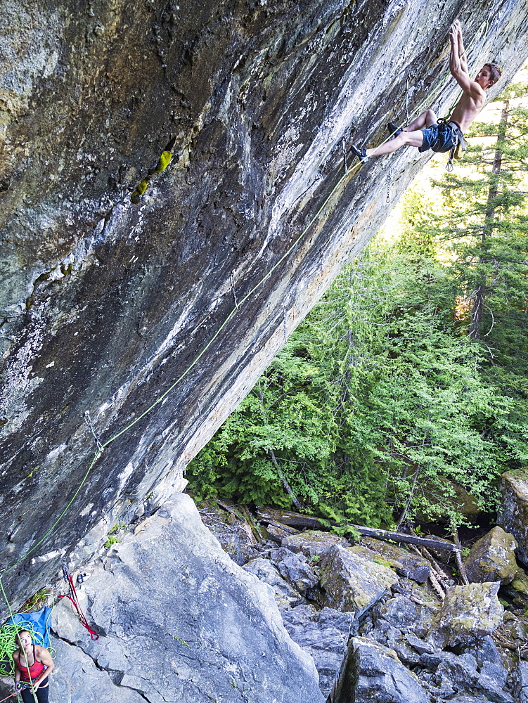 Girl watching boy climbing rock