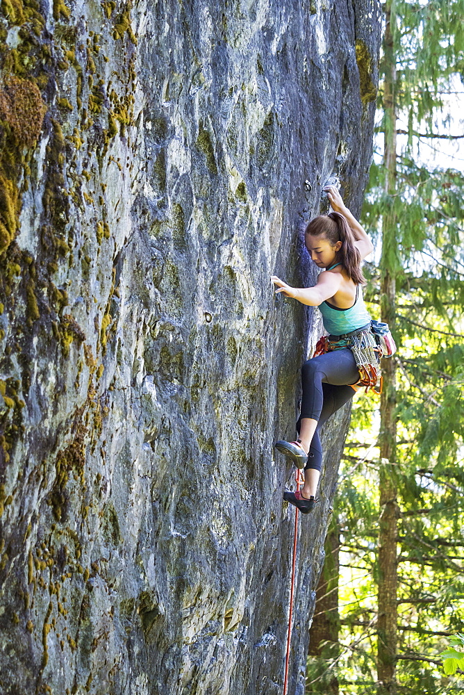 Mixed race girl climbing rock